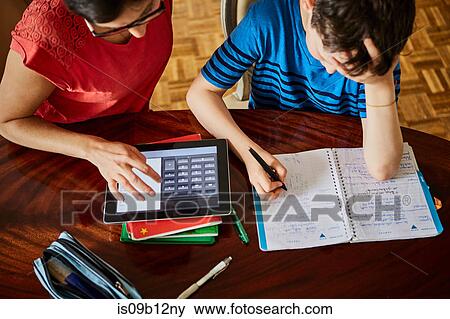 High angle view of mother at dining table helping son with homework View Large Photo Image Stock Photo - High angle view of mother at dining table helping son with homework. Fotosearch