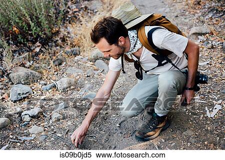 Stock Photography - Hiker crouching picking up stones, Malibu Canyon, California, USA. Fotosearch
