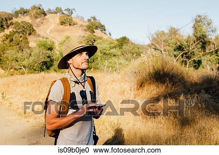 Hiker holding smartphone looking away, Malibu Canyon, California, USA View Large Photo Image Stock Image - Hiker holding smartphone looking away, Malibu Canyon, California, USA. Fotosearch