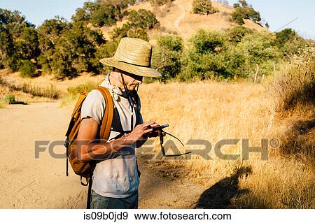 Hiker looking down at smartphone, Malibu Canyon, California, USA View Large Photo Image Stock Photo - Hiker looking down at smartphone, Malibu Canyon, California, USA. Fotosearch