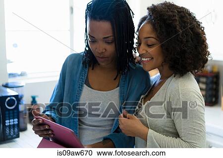 Lesbian couple in kitchen, looking at digital tablet View Large Photo Image Stock Image - Lesbian couple in kitchen, looking at digital tablet. Fotosearch