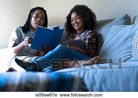 Lesbian couple relaxing sofa, reading book and using digital tablet View Large Photo Image Stock Image - Lesbian couple relaxing sofa, reading book and using digital tablet. Fotosearch
