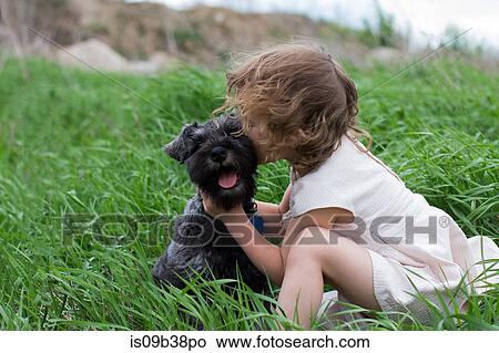 Picture - Little girl kissing pet dog on grass field. Fotosearch