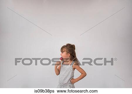 Little girl licking lollipop against white background View Large Photo Image Stock Photograph - Little girl licking lollipop against white background. Fotosearch
