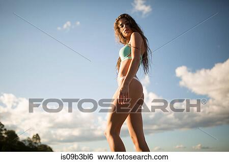 Stock Photograph - Low angle portrait of young woman with long hair in bikini at coast, Santa Rosa Beach, Florida, USA. Fotosearch