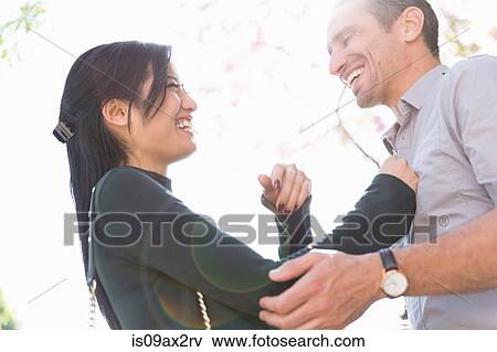 Stock Photo - Low angle view of couple face to face smiling. Fotosearch