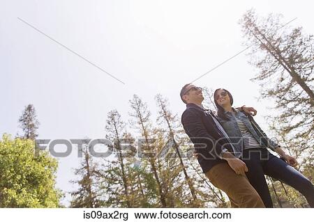Stock Image - Low angle view of couple strolling wearing sunglasses. Fotosearch