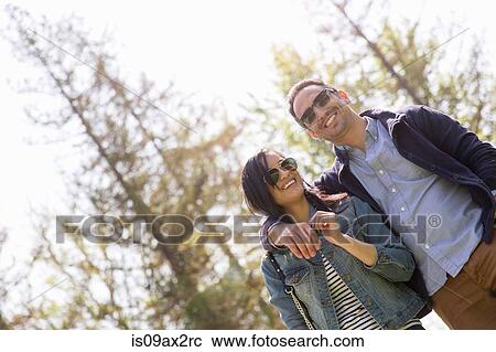 Low angle view of couple wearing sunglasses View Large Photo Image Stock Image - Low angle view of couple wearing sunglasses. Fotosearch