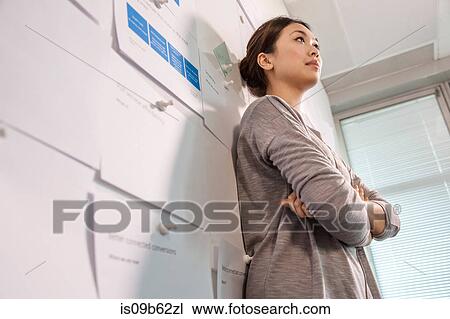 Low angle view of female digital designer leaning against office wall View Large Photo Image Stock Image - Low angle view of female digital designer leaning against office wall. Fotosearch