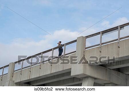 Low angle view of woman on bridge taking photograph, Destin, Gulf of Mexico, USA View Large Photo Image Stock Image - Low angle view of woman on bridge taking photograph, Destin, Gulf of Mexico, USA. Fotosearch