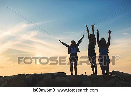 Low angle view of women on rocks in silhouette arms raised View Large Photo Image Stock Image - Low angle view of women on rocks in silhouette arms raised. Fotosearch