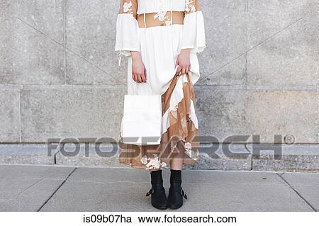 Stock Image - Low section of woman holding shopping bag. Fotosearch
