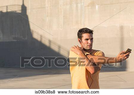 Male athlete listening to music and stretching, Van Nuys, California, USA View Large Photo Image Stock Photo - Male athlete listening to music and stretching, Van Nuys, California, USA. Fotosearch