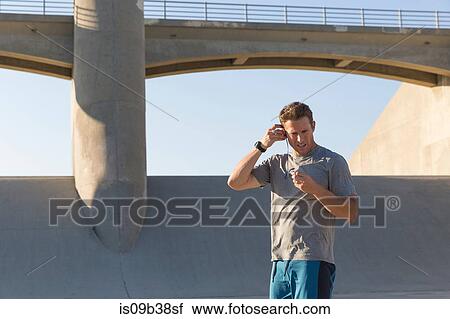 Male athlete putting on earphones, Van Nuys, California, USA View Large Photo Image Stock Image - Male athlete putting on earphones, Van Nuys, California, USA. Fotosearch