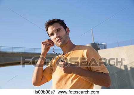 Male athlete putting on earphones, Van Nuys, California, USA View Large Photo Image Stock Photo - Male athlete putting on earphones, Van Nuys, California, USA. Fotosearch