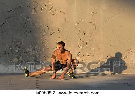 Male athlete stretching in front of concrete wall View Large Photo Image Stock Image - Male athlete stretching in front of concrete wall. Fotosearch