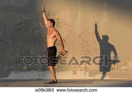 Male athlete stretching in front of concrete wall View Large Photo Image Stock Image - Male athlete stretching in front of concrete wall. Fotosearch