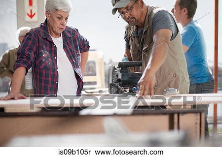 Stock Photography - Male carpenter using power saw in furniture making workshop. Fotosearch