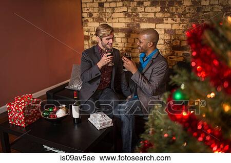 Male couple celebrating Christmas, holding wine glasses, making a toast View Large Photo Image Stock Image - Male couple celebrating Christmas, holding wine glasses, making a toast. Fotosearch