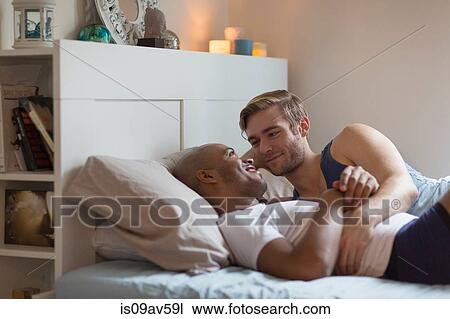Male couple lying in bed together, face to face View Large Photo Image Stock Image - Male couple lying in bed together, face to face. Fotosearch
