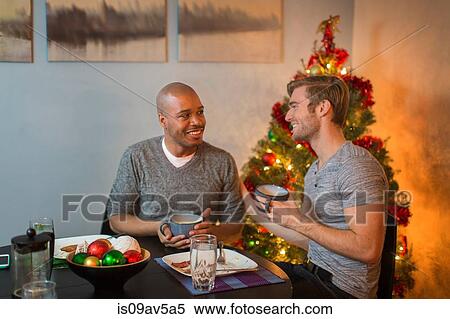 Male couple sitting at table, having breakfast together, Christmas tree in background View Large Photo Image Stock Photography - Male couple sitting at table, having breakfast together, Christmas tree in background. Fotosearch