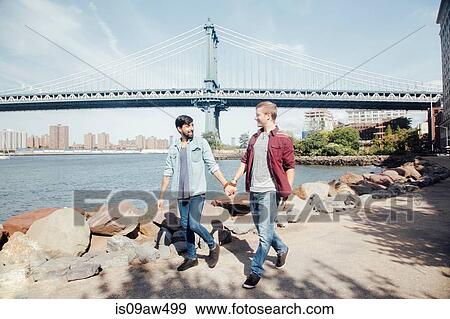 Male couple strolling on riverside by Manhattan Bridge, New York, USA View Large Photo Image Stock Photo - Male couple strolling on riverside by Manhattan Bridge, New York, USA. Fotosearch