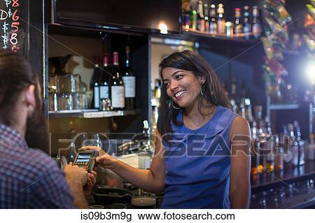Male customer paying by credit card machine to barmaid in public house View Large Photo Image Stock Image - Male customer paying by credit card machine to barmaid in public house. Fotosearch