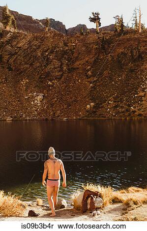 Stock Photography - Male hiker in swimming trunks by lake drying face, Mineral King, Sequoia National Park, California, USA. Fotosearch