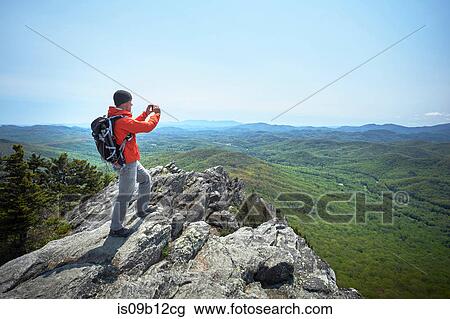 Stock Image - Male hiker taking smartphone photographs from ridge, Blue Ridge Mountains, North Carolina, USA. Fotosearch