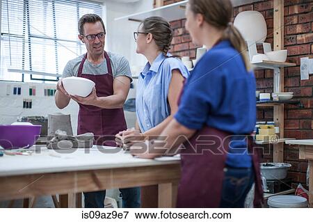 Male potter explaining bowl to trainees in workshop View Large Photo Image Stock Photo - Male potter explaining bowl to trainees in workshop. Fotosearch