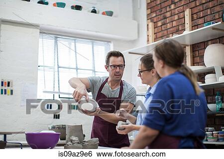 Male potter showing trainees bowl in workshop View Large Photo Image Stock Photograph - Male potter showing trainees bowl in workshop. Fotosearch
