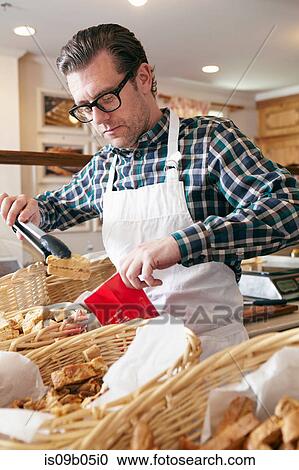 Male worker in bakery, putting fresh baked goods into paper bag for customer View Large Photo Image Stock Image - Male worker in bakery, putting fresh baked goods into paper bag for customer. Fotosearch