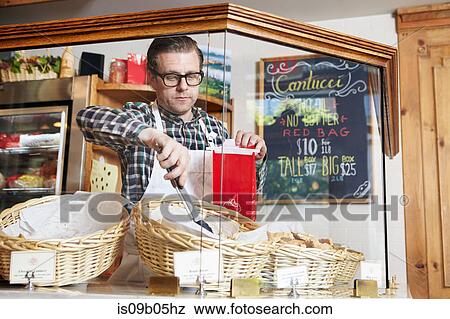 Male worker in bakery, putting fresh baked goods into paper bag for customer View Large Photo Image Stock Photo - Male worker in bakery, putting fresh baked goods into paper bag for customer. Fotosearch