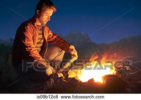 Man crouching by campfire at night, Jackson, Wyoming, USA View Large Photo Image Stock Photo - Man crouching by campfire at night, Jackson, Wyoming, USA. Fotosearch