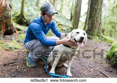 Man crouching in forest stroking dog View Large Photo Image Stock Image - Man crouching in forest stroking dog. Fotosearch