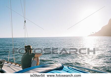Stock Photograph - Man enjoying sunset on sailboat, San Diego Bay, California, USA. Fotosearch