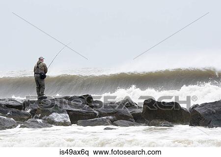 Man fishing from rocks in stormy ocean waves, Long Beach, New York, USA View Large Photo Image Stock Photography - Man fishing from rocks in stormy ocean waves, Long Beach, New York, USA. Fotosearch