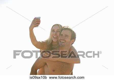 Man giving woman piggyback using smartphone to take selfie, smiling View Large Photo Image Stock Image - Man giving woman piggyback using smartphone to take selfie, smiling. Fotosearch