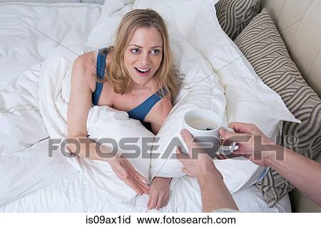 Man handing coffee to surprised woman in bed View Large Photo Image Stock Image - Man handing coffee to surprised woman in bed. Fotosearch