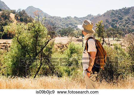 Man hiking looking away at view of mountains, Malibu Canyon, California, USA View Large Photo Image Stock Photo - Man hiking looking away at view of mountains, Malibu Canyon, California, USA. Fotosearch