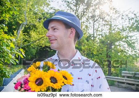 Man holding flowers looking away View Large Photo Image Stock Image - Man holding flowers looking away. Fotosearch