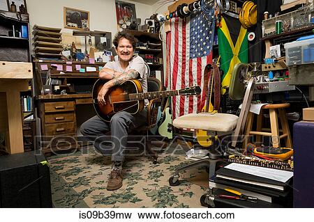 Man holding guitar looking at camera smiling View Large Photo Image Stock Photo - Man holding guitar looking at camera smiling. Fotosearch