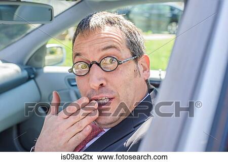 Stock Photo - Man in car wearing eye glasses, hand over mouth looking at camera. Fotosearch