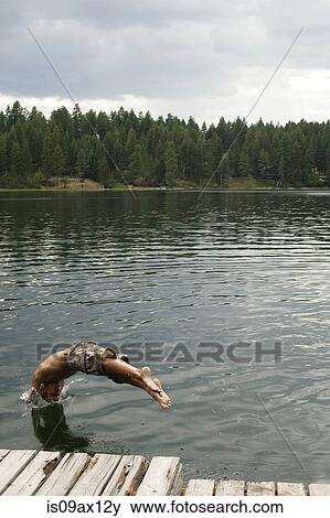 Man in mid air diving into lake View Large Photo Image Stock Photo - Man in mid air diving into lake. Fotosearch