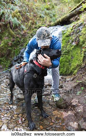 Man in stream kissing dog View Large Photo Image Stock Photo - Man in stream kissing dog. Fotosearch