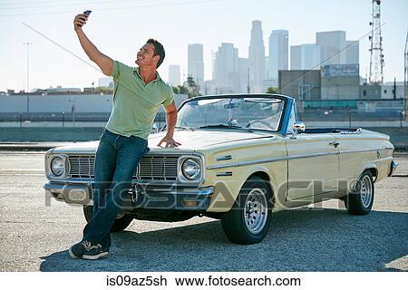 Man leaning against convertible car taking selfie, Los Angeles, California, USA View Large Photo Image Stock Image - Man leaning against convertible car taking selfie, Los Angeles, California, USA. Fotosearch