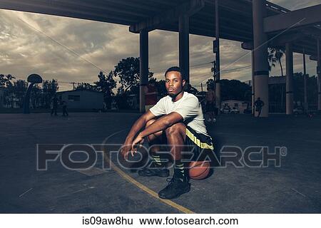 Man on basketball court sitting on basketball looking at camera View Large Photo Image Stock Photograph - Man on basketball court sitting on basketball looking at camera. Fotosearch