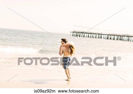 Man on beach carrying woman on shoulder to ocean, Coney island, Brooklyn, New York, USA View Large Photo Image Picture - Man on beach carrying woman on shoulder to ocean, Coney island, Brooklyn, New York, USA. Fotosearch