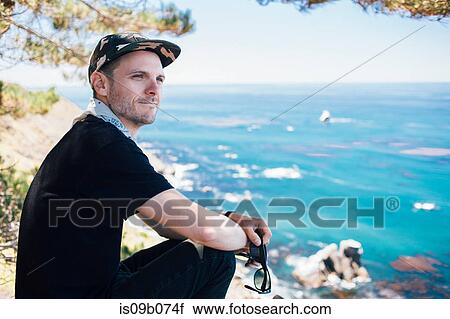 Stock Image - Man on coast looking over his shoulder, Big Sur, California, USA. Fotosearch