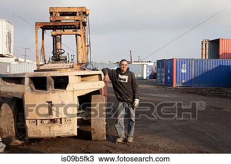 Man on construction site standing by heavy machinery View Large Photo Image Stock Image - Man on construction site standing by heavy machinery. Fotosearch